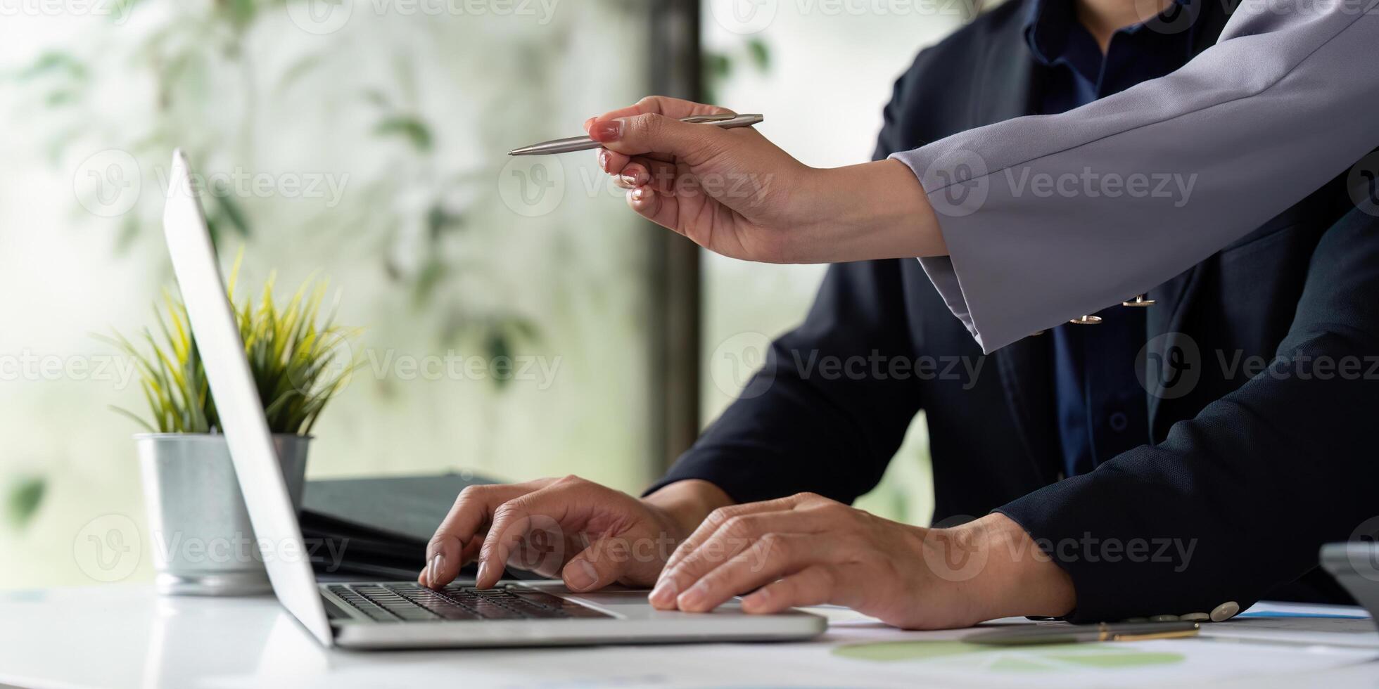 Technical Support and Collaboration. A professional woman guiding her colleague in using a laptop during a work session. photo