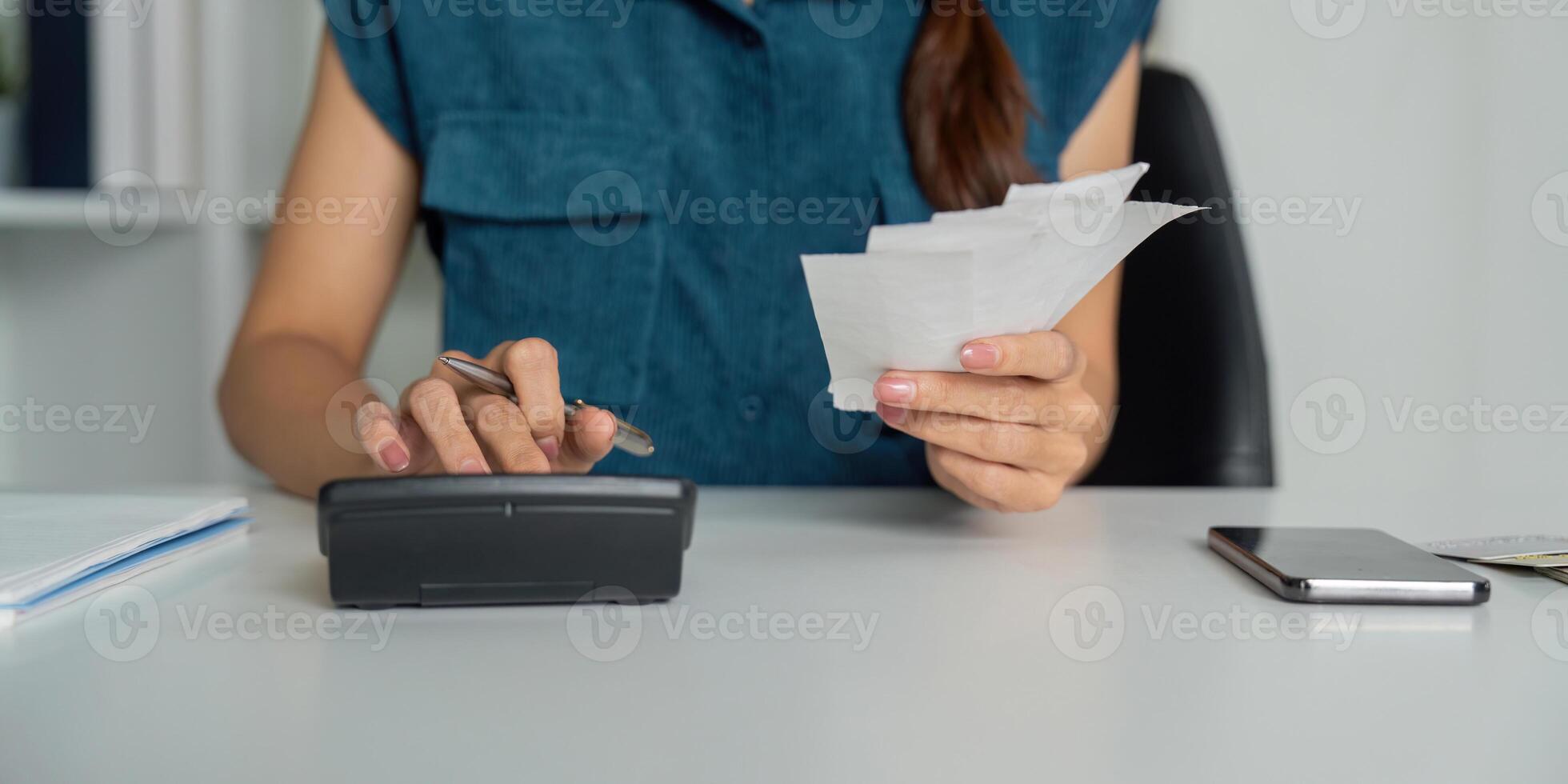 Smart Budgeting and Expense Management. A woman focused on organizing her finances using a calculator and handling receipts. photo