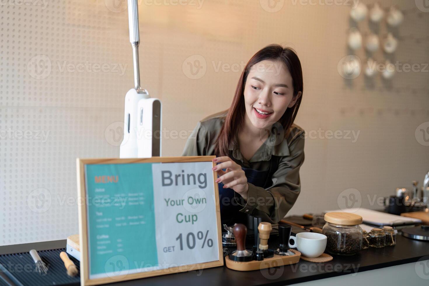 Promoting Eco-Conscious Choices. A barista setting up a sign to encourage customers to bring their own cups for discounts. photo