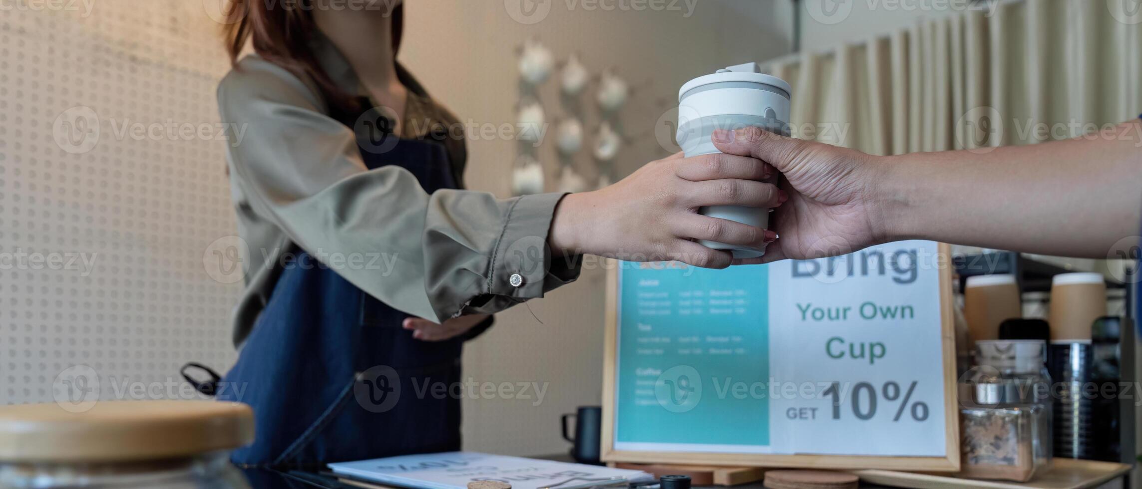 Customer Engagement and Discounts. A barista handing over a reusable cup with a discount offer. photo