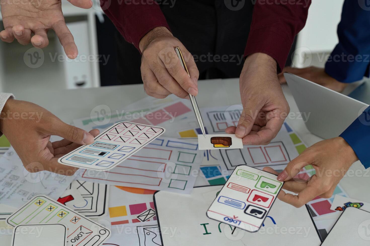 Creative Teamwork in UX UI Design. Designers engaging in a lively discussion over digital prototypes and sketches. photo