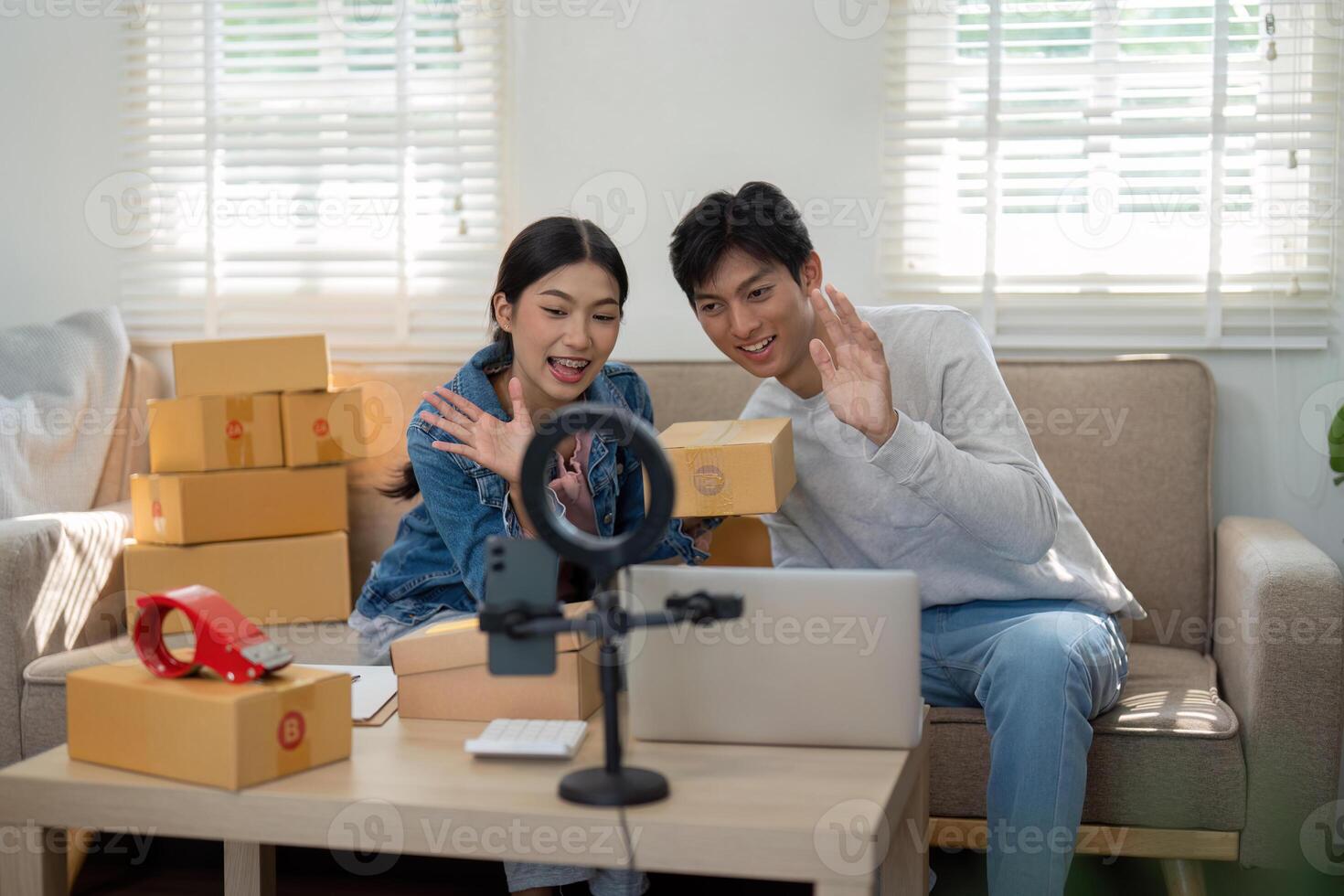 Virtual Engagement and Product Presentation. The duo waves at their audience during a live unboxing session, showcasing their newly arrived products. photo