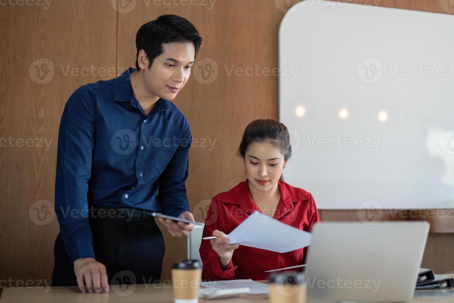 Analysis and Data Presentation. A man and woman assess financial documents in an office workspace. photo