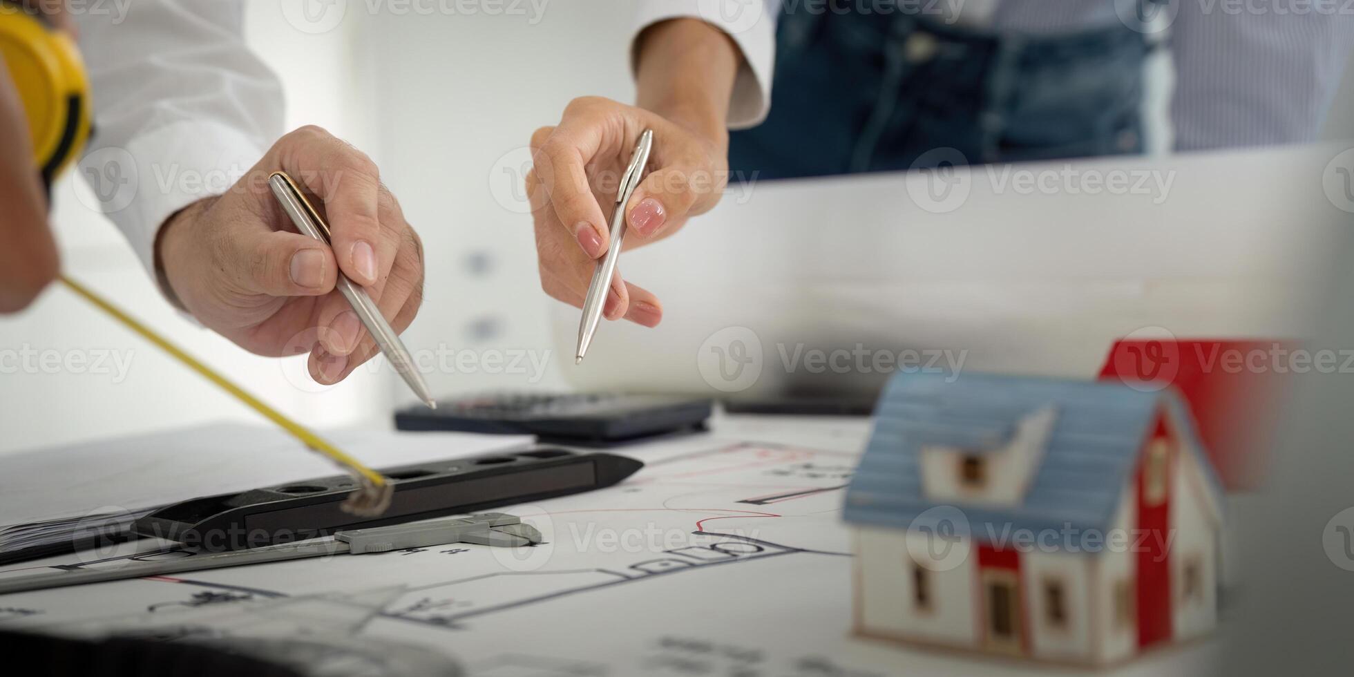Collaboration and Construction Planning. Colleagues discussing architectural plans with a miniature house on the table. photo