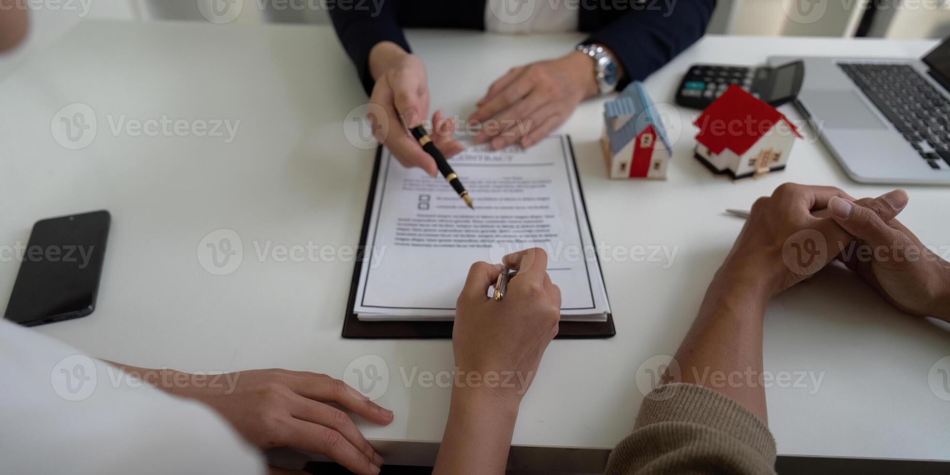 Real Estate Negotiation and Client Engagement. A couple reviewing and signing important documents with an agent at a modern office. photo