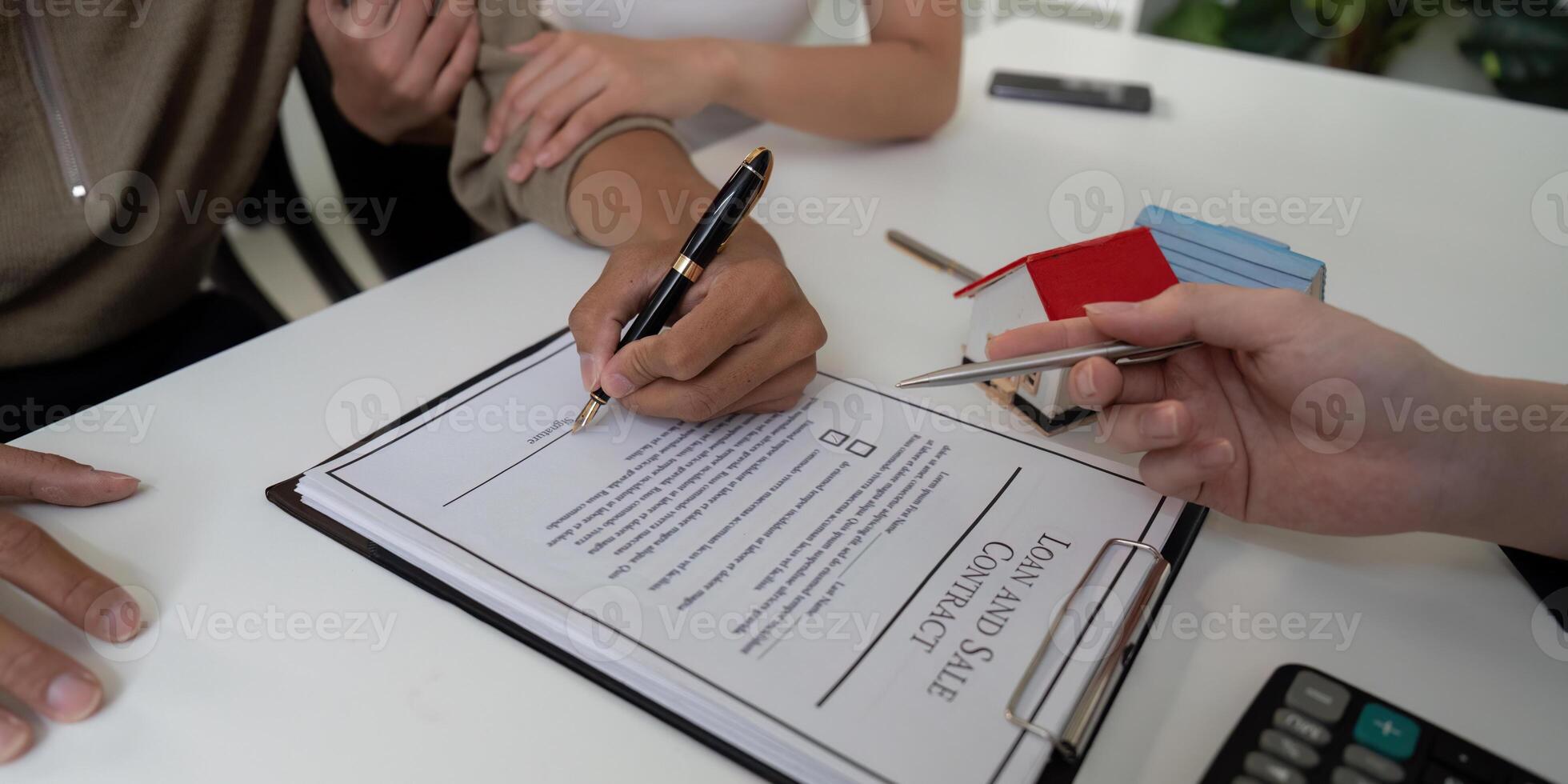Real Estate and Contract Signing. A couple finalizing their home purchase agreement with a real estate agent. photo