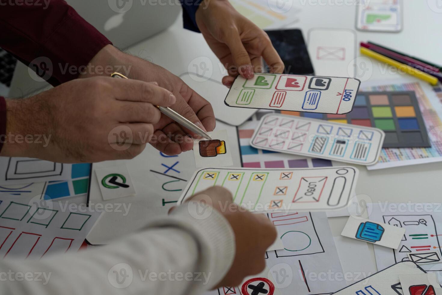 UX Design Collaboration and Prototyping. Team members discussing digital interface designs with sketches and icons. photo