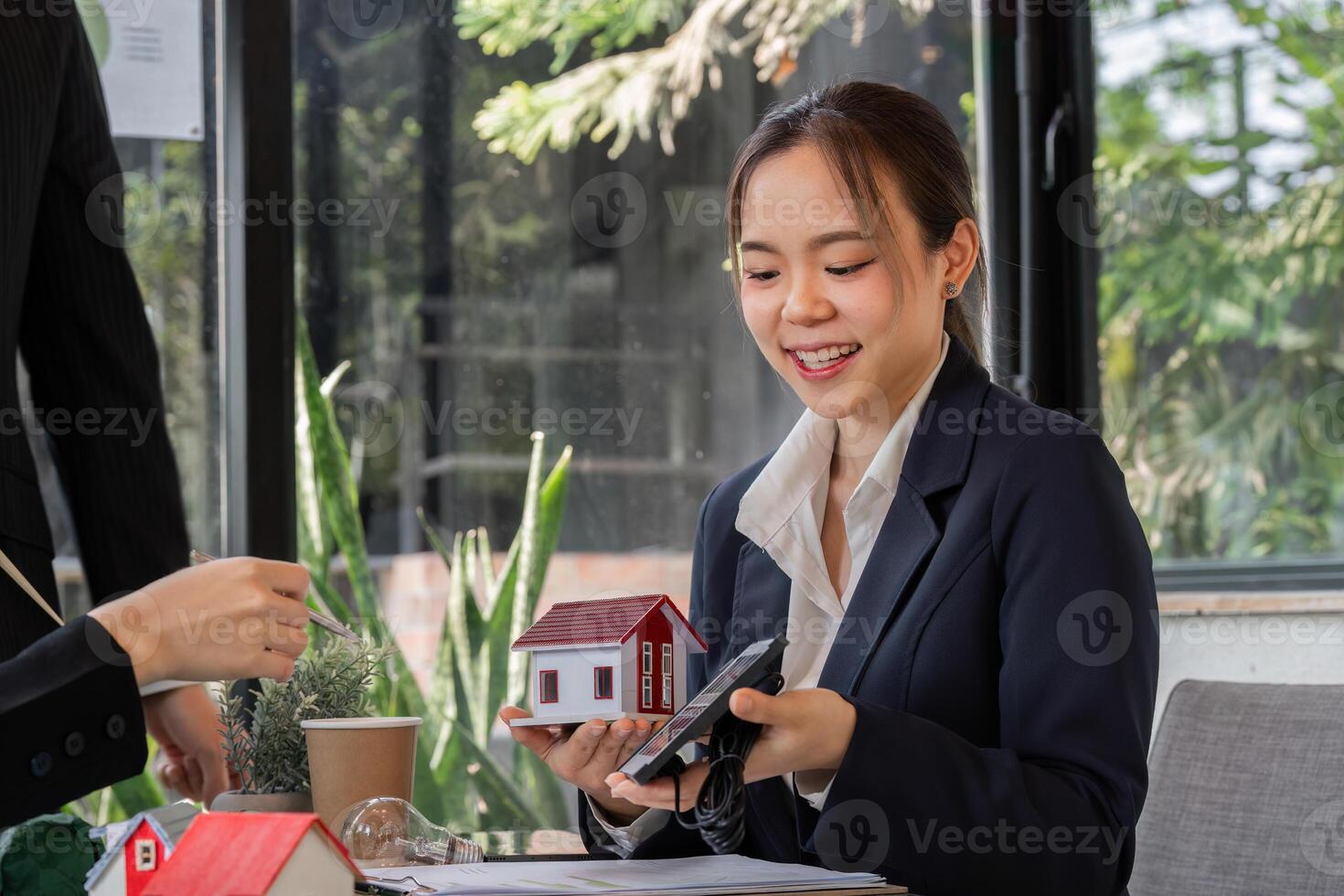 Sustainability and Innovation. A young professional presenting a model of an eco-friendly house during a meeting. photo
