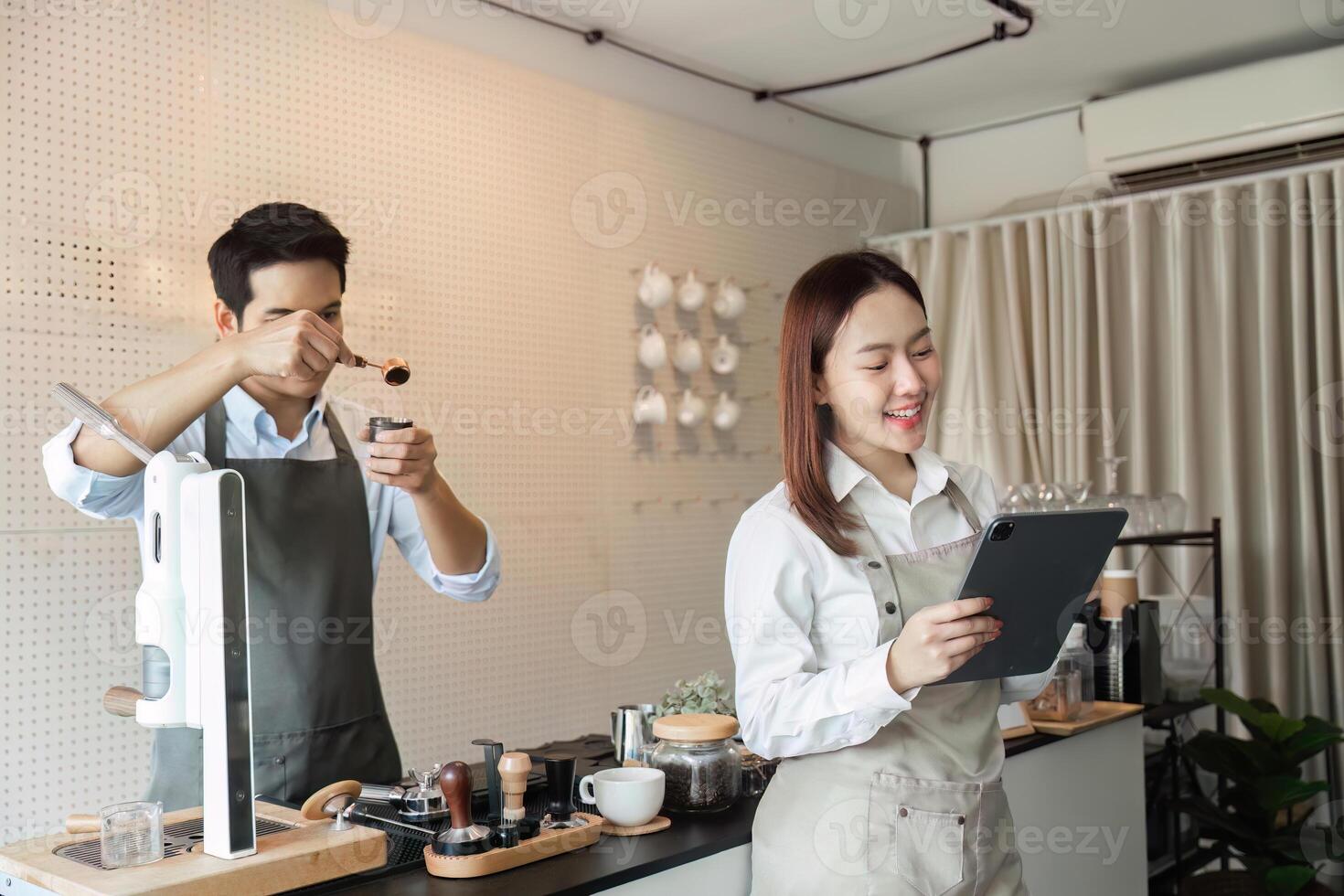 Barista Craftsmanship and Technology. A skilled barista prepares coffee while another reviews orders on a tablet. photo