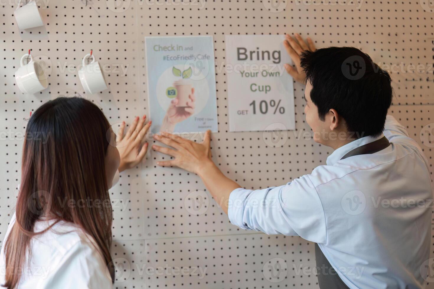 Sustainability and Cafe Culture. Employees promoting eco-friendly practices by encouraging customers to bring their own cups. photo