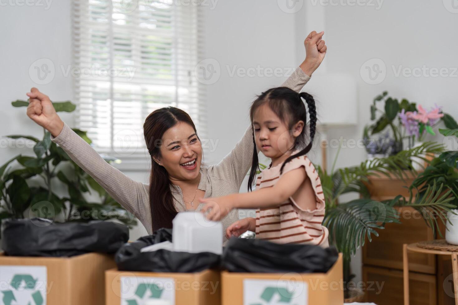 Joyful Recycling and Teaching Moments. A mother celebrates her daughters involvement in a recycling project, emphasizing eco-friendly practices at home. photo