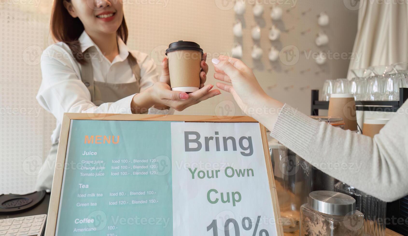 Eco-Consciousness and Community Engagement. A barista promotes the bring-your-own-cup initiative to customers. photo
