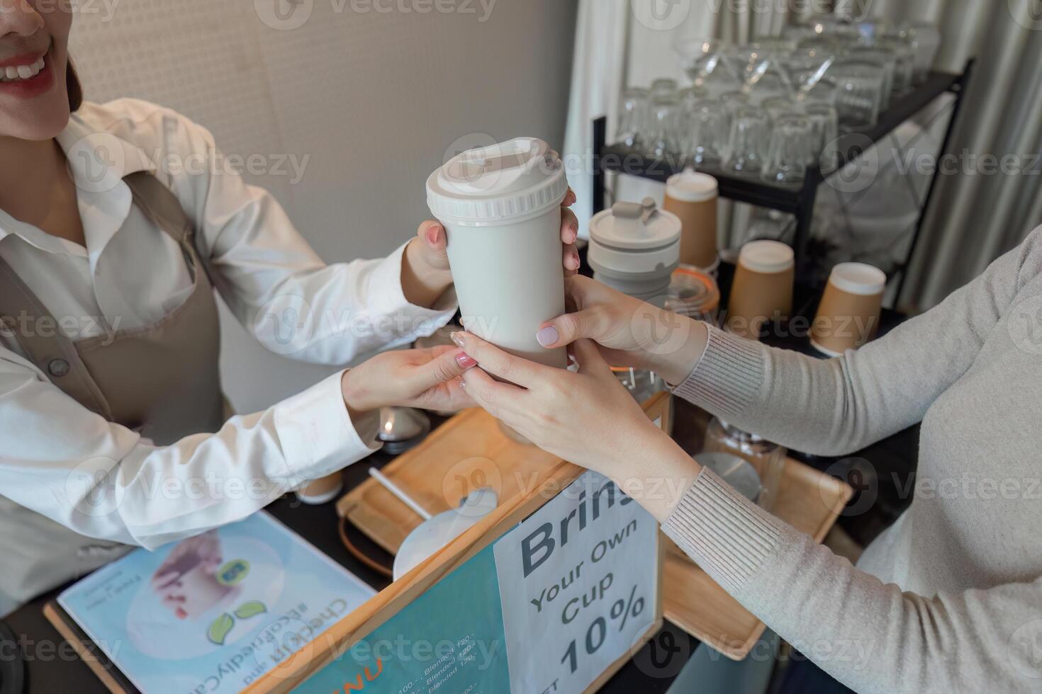 Sustainability and Coffee Culture. A barista handing over a reusable cup to a customer promoting eco-friendly practices. photo