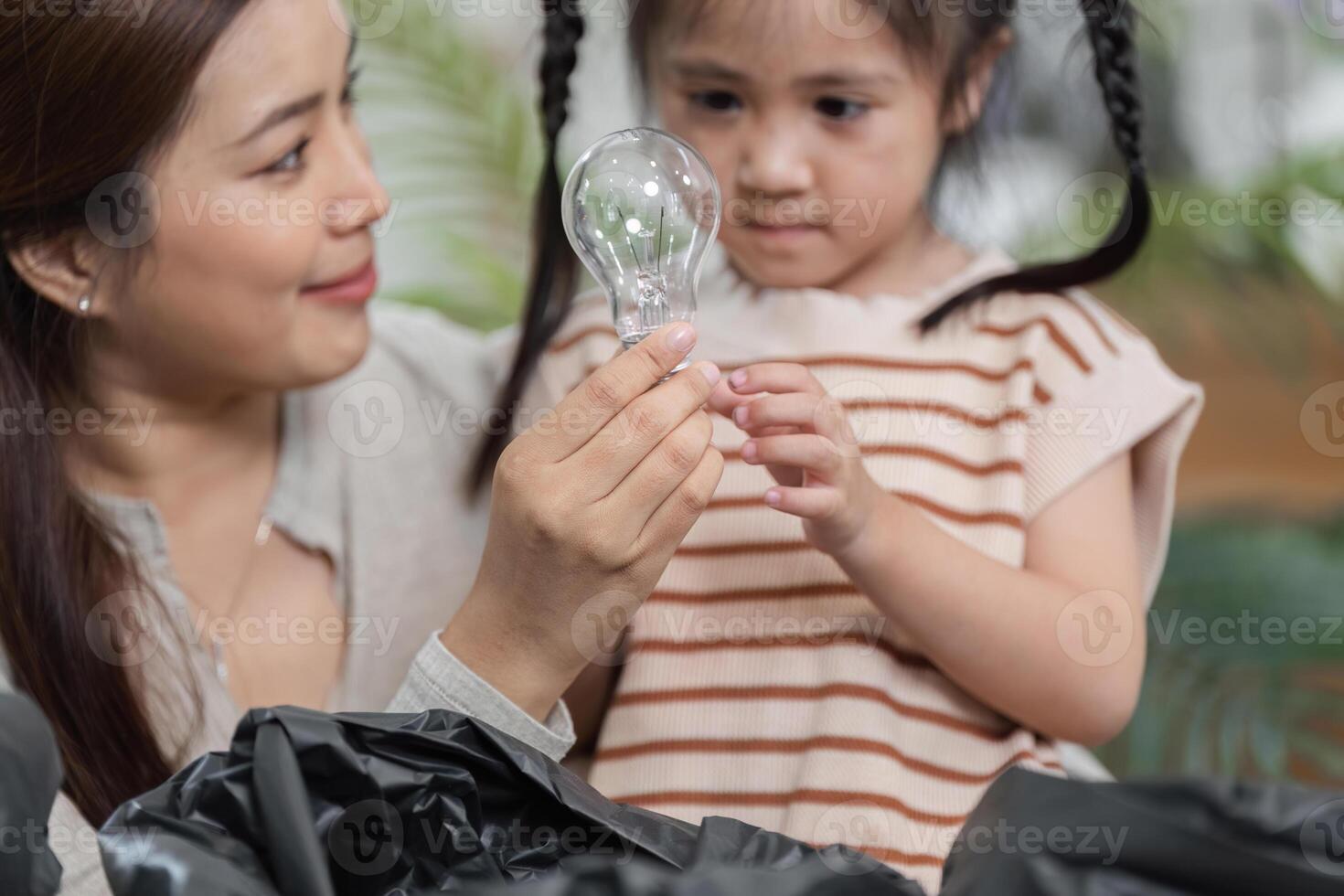 Learning About Sustainability and Recycling. A mother explains the recycling process using a light bulb in their eco-friendly project. photo