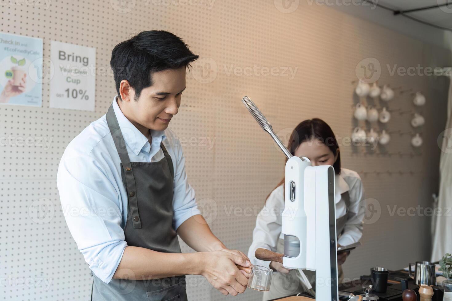 Coffee Preparation and Teamwork. A barista working behind the counter while another assists in making coffee drinks. photo