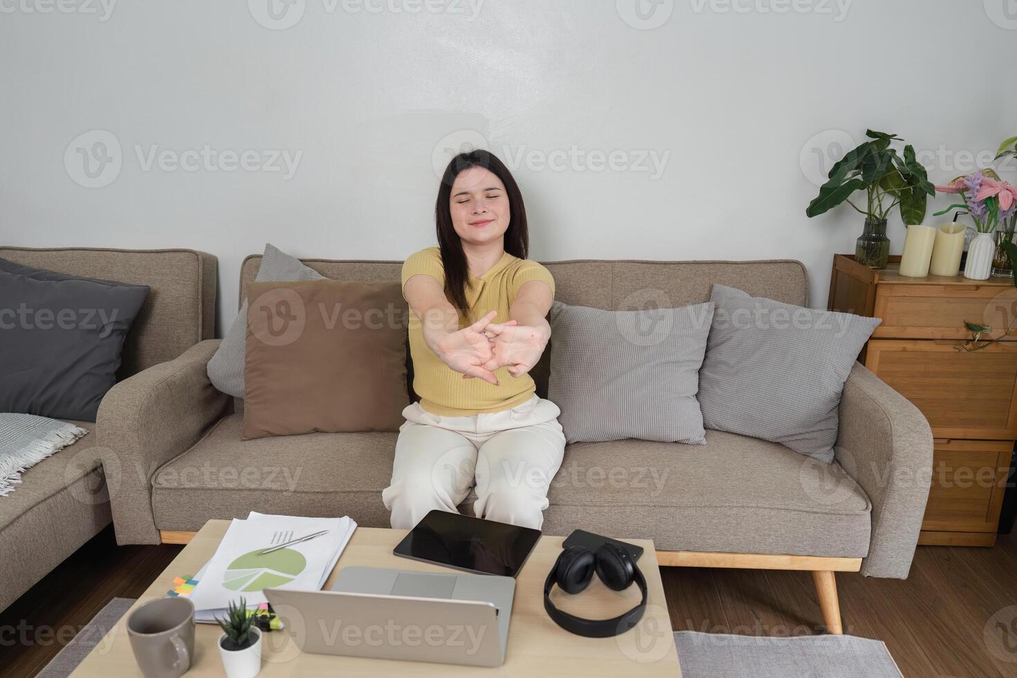 Remote Work and Home Comfort. A woman stretching while working from her cozy living room. photo