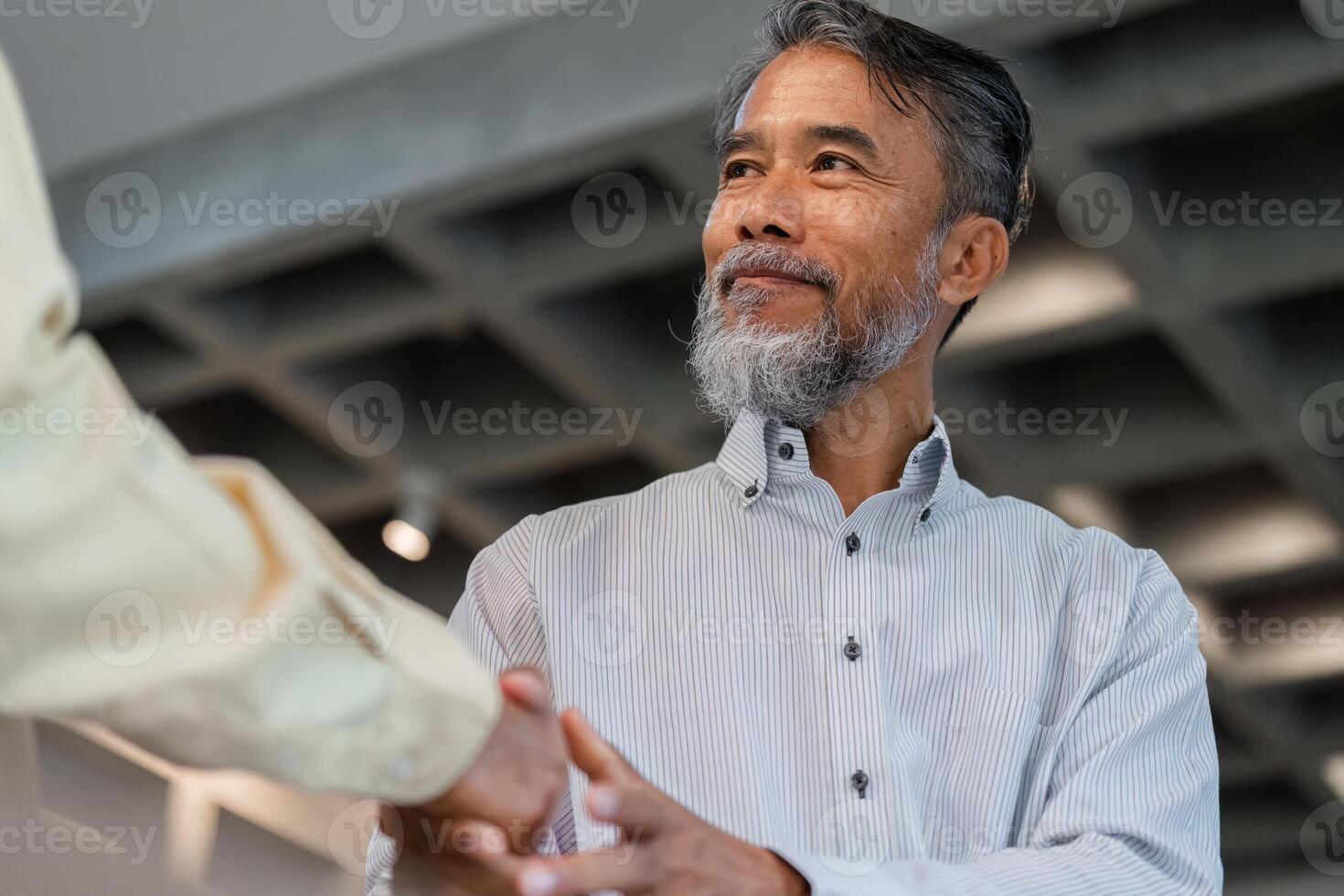 Professional Networking and Engagement. A senior man actively shaking hands with a business consultant. photo