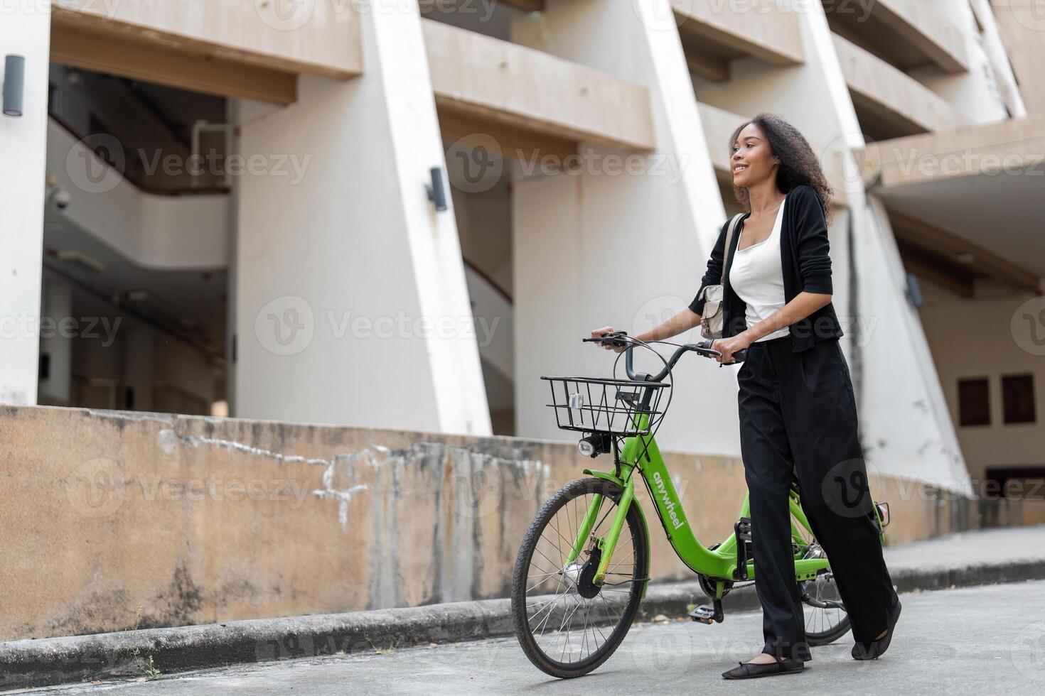 Sustainable Transportation and Urban Lifestyle. A woman leisurely walks her green bicycle down an urban street, embracing eco-friendly commuting in a stylish outfit. photo