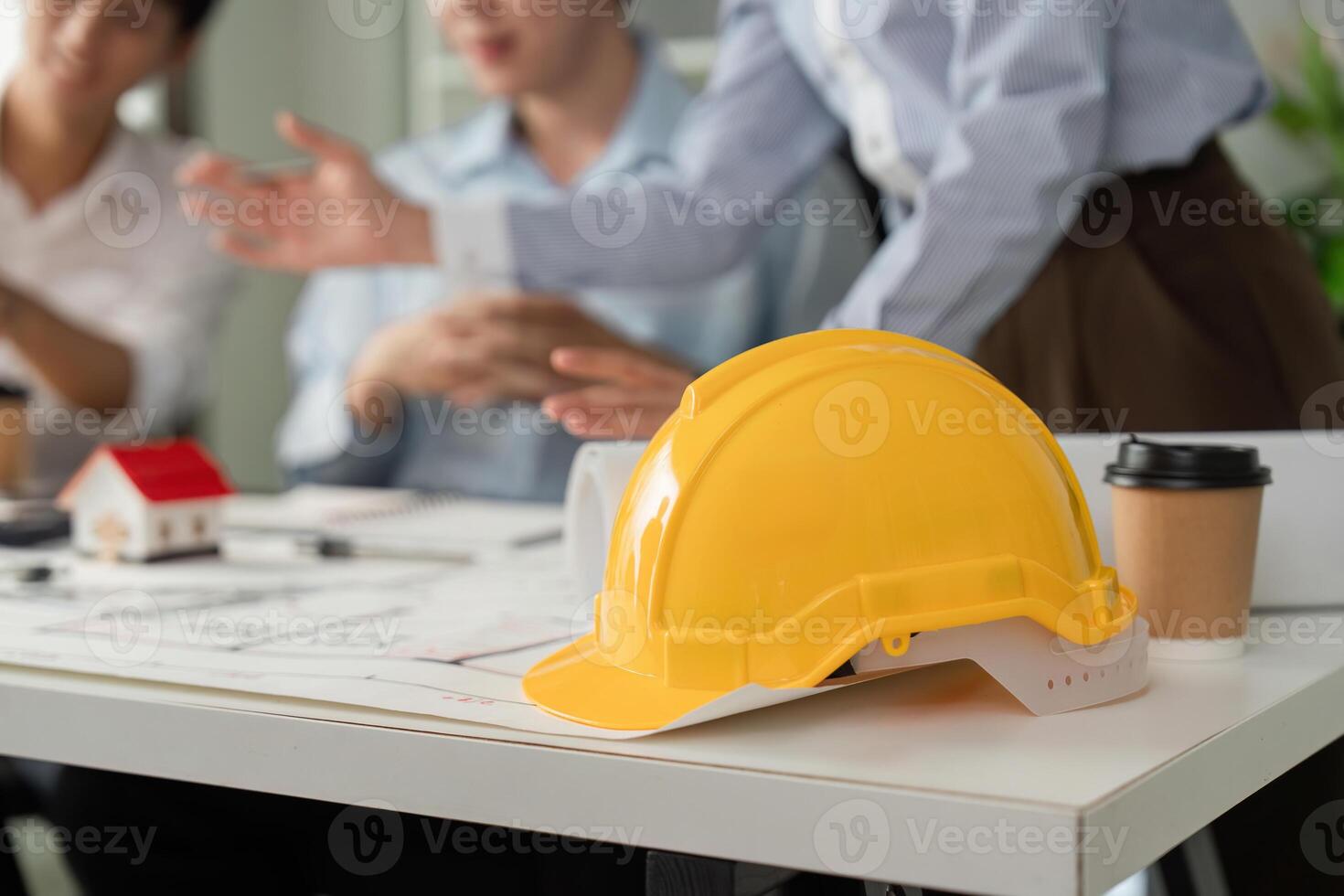 Construction Meeting and Safety Protocols. A hard hat rests on the table during a design discussion among building professionals. photo