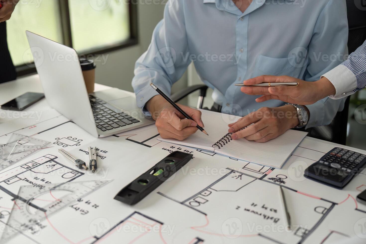Design and Drafting. An architect taking notes while collaborating on construction plans and specifications. photo