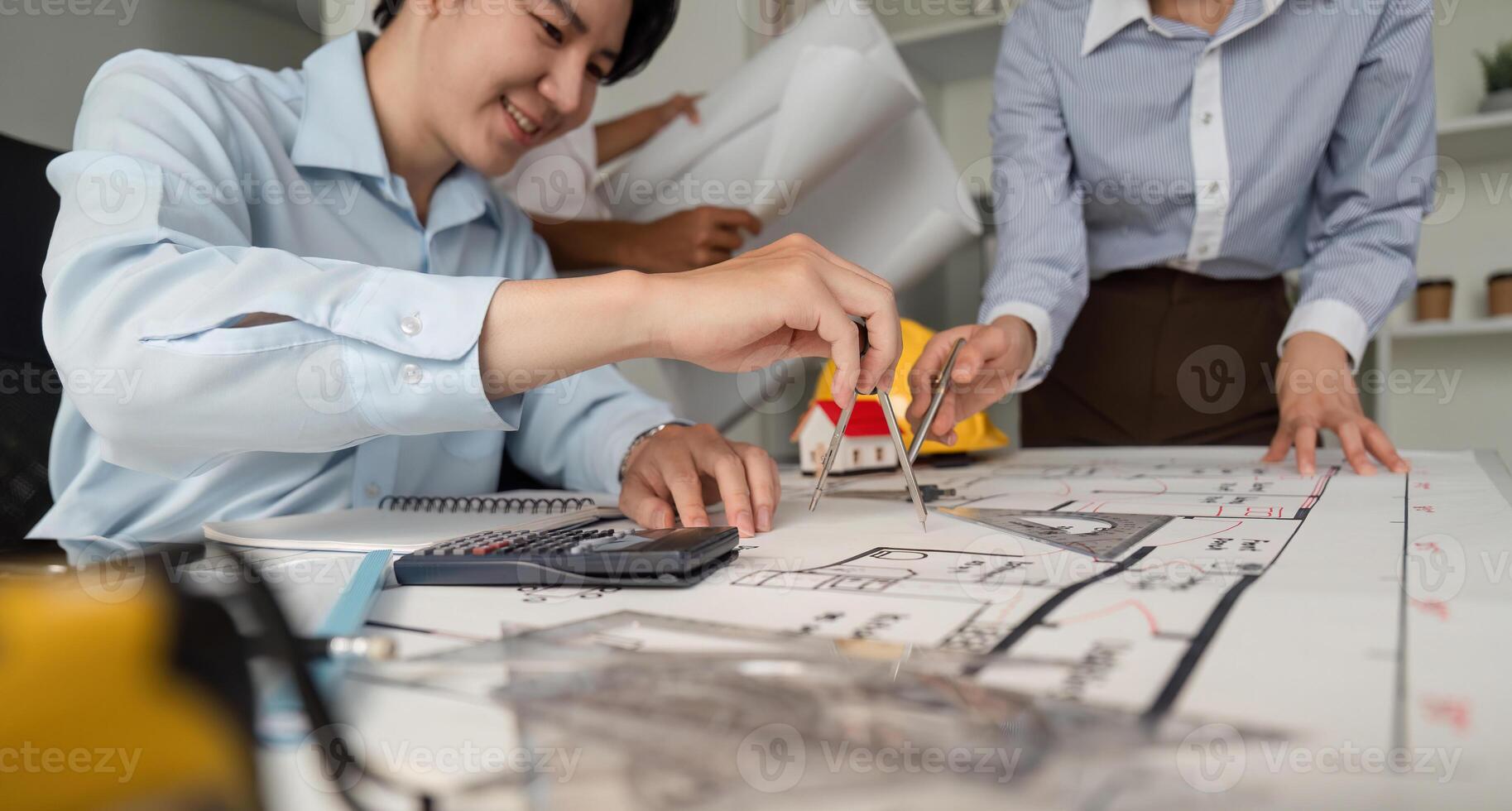 Teamwork and Blueprint Analysis. A focused architect using a compass to finalize the layout of a building design, collaborating with colleagues. photo