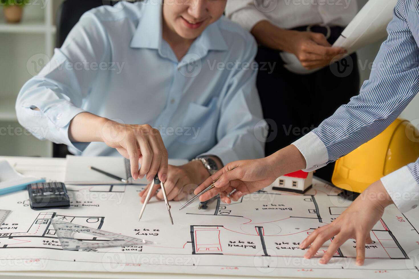 Collaboration and Architectural Planning. Two professionals collaborating on building design plans with materials and tools. photo