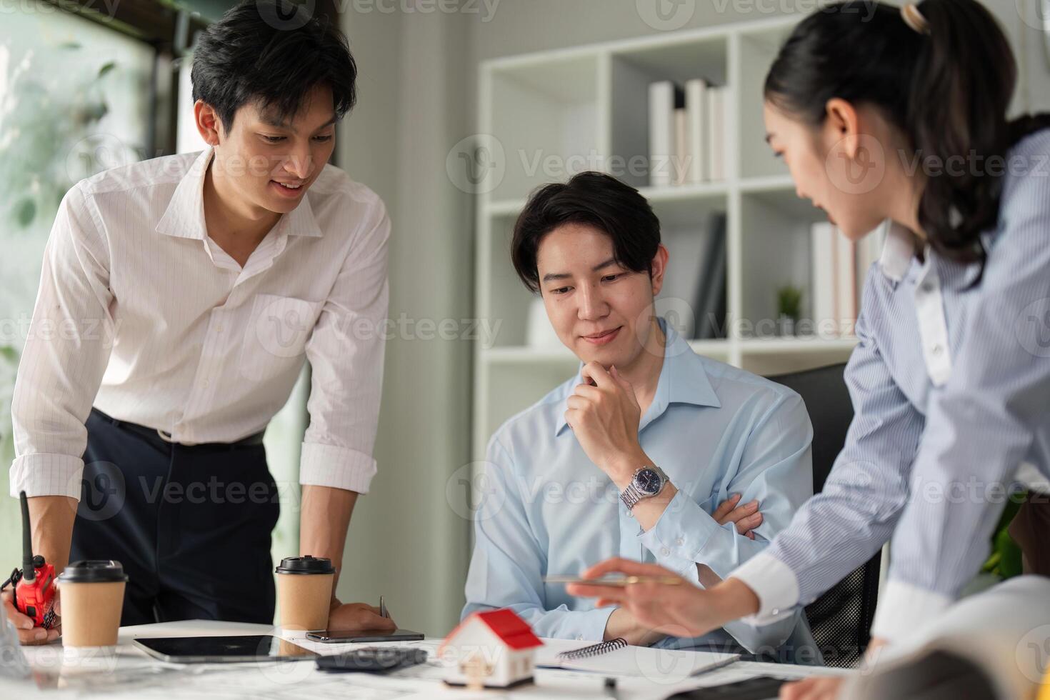 Design Presentation and Collaboration. A professional team discussing a model house design with blueprints on the table. photo