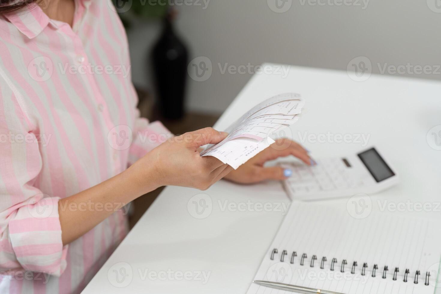 Analyzing Expenditures and Home Office Routine. A woman calculating expenses with her receipts and calculator at her desk. photo