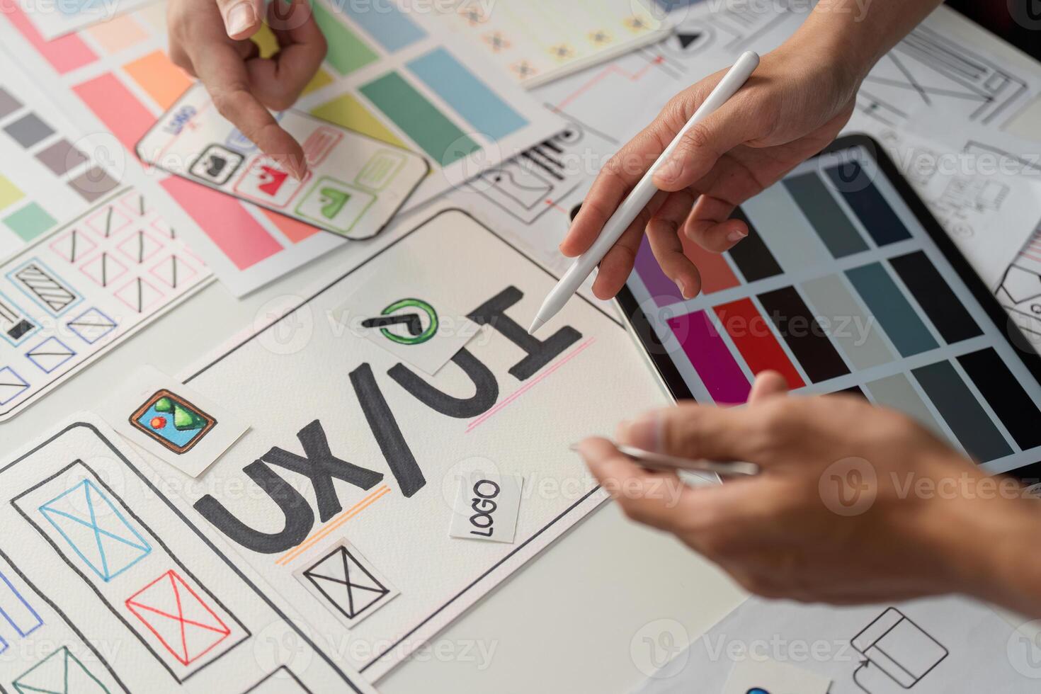 UXUI Design and Collaboration. Creative professionals engaged in user experience and interface design brainstorming on a table full of sketches and wireframes. photo
