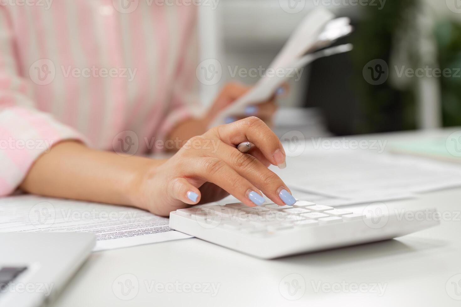 Home Office and Productivity. An individual focused on calculations with a calculator in a bright home office setting. photo