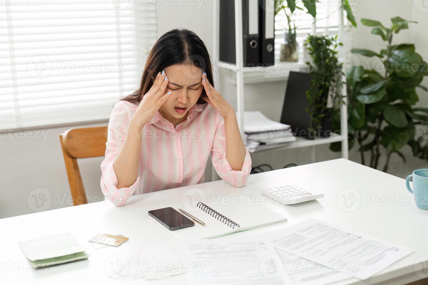 Home Office and Stress Management. A woman deals with the stress of financial paperwork while sitting at her home desk, looking overwhelmed. photo