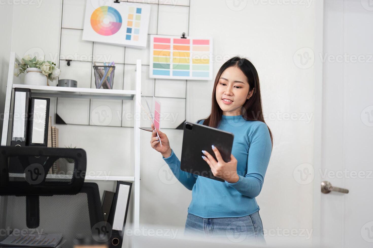 Design Process and Color Evaluation. A designer engages with her tablet and swatches to finalize design elements. photo