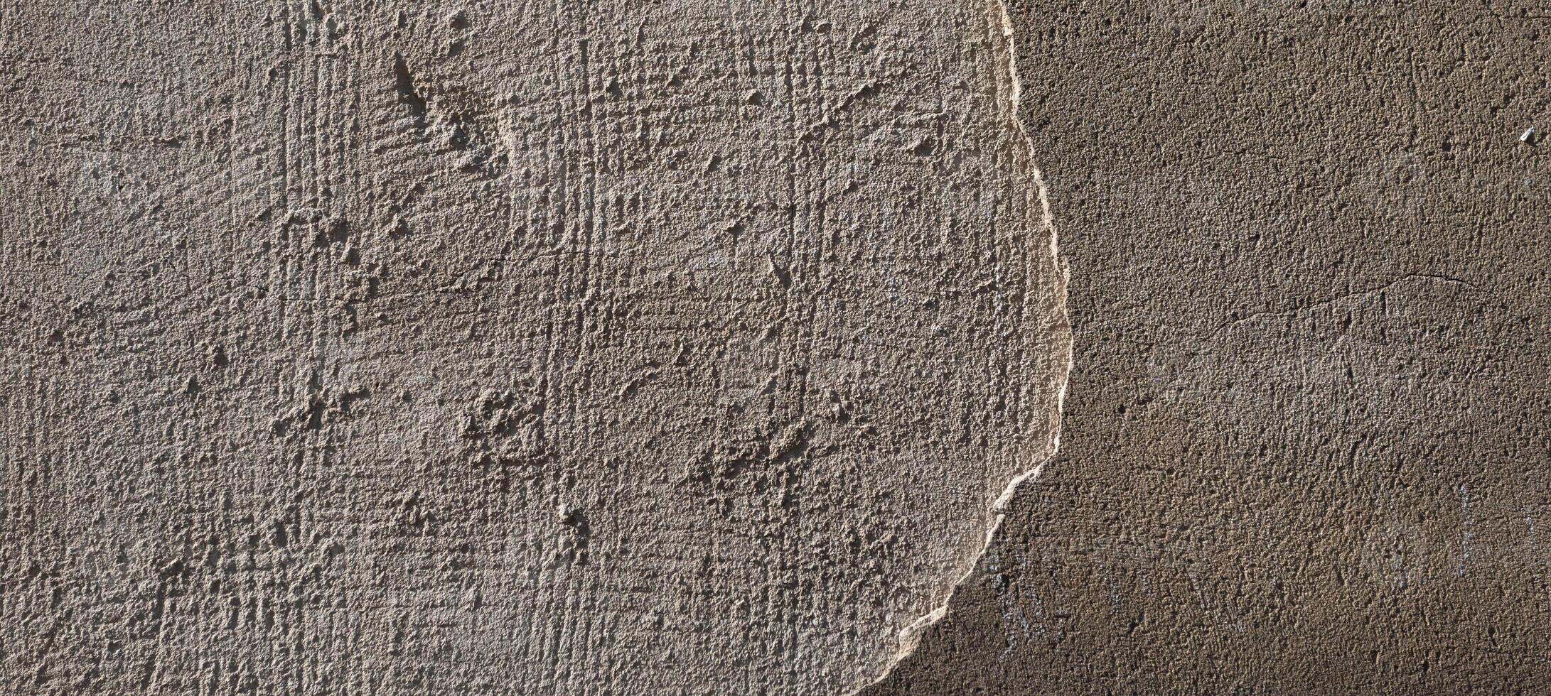 An old concrete wall shows a textured surface with a rough edge and a smooth area. photo