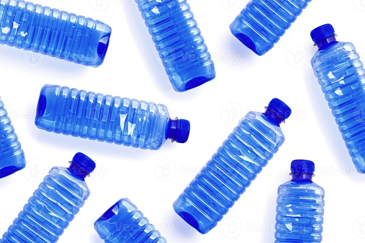 Pattern with blue plastic bottles isolated on white background, top view empty plastic bottle for water half litre, minimal style design. Pollution, plastic garbage, environmental protection concept photo