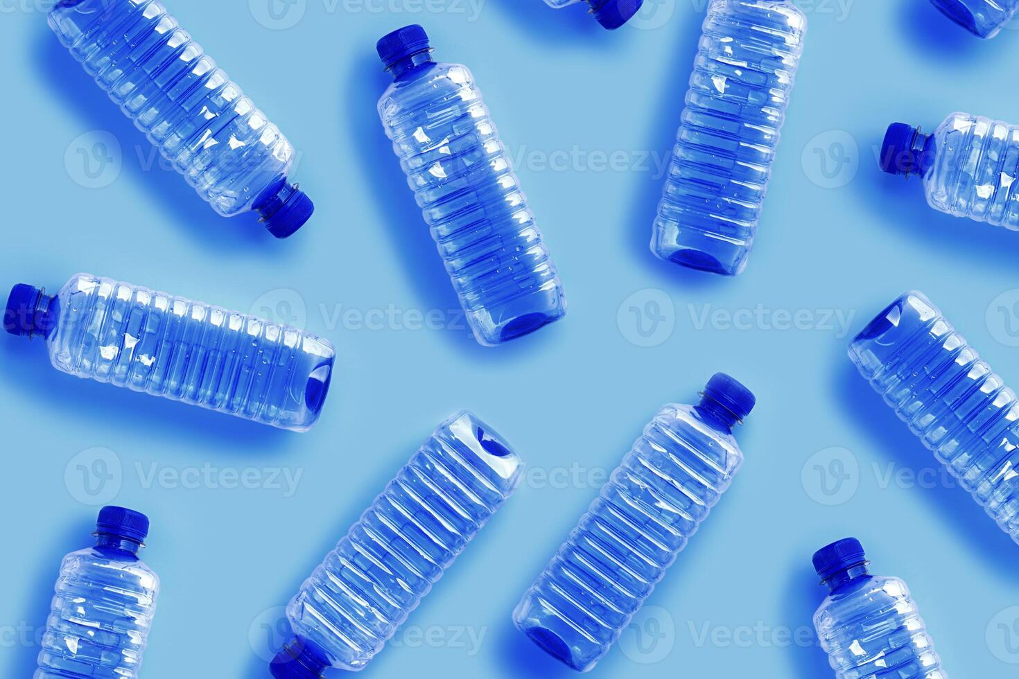 Clear single-use plastic water bottles on light blue background close-up pattern, minimal style aesthetic photo, top view bottled water, Pollution, environmental protection, plastic waste photo