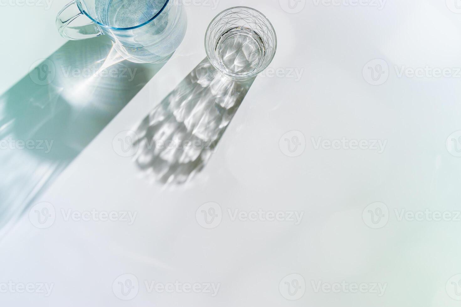 Water Glasses and water jug with Shadows, sunlight Reflection on white background, colored photo minimal style, aesthetic summer still life, refraction throug crystal shine cups, caustics