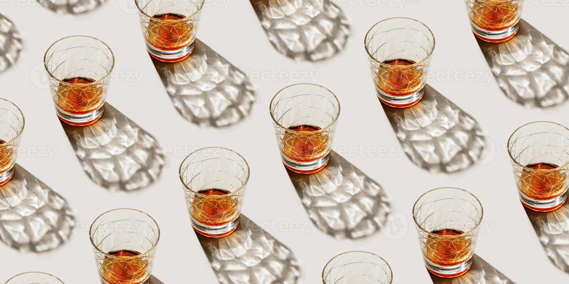 Crystal Whiskey Glasses at sunlight, repeated pattern on beige background, minimal neutral banner, aesthetic top view summer still life, refraction at shine alcohol drink, dark shadow, caustics photo