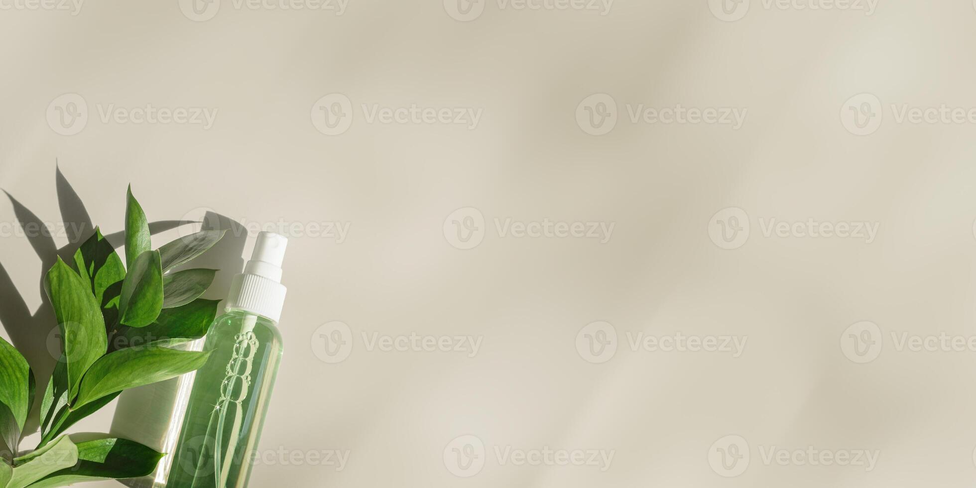 Transparent Cosmetic spray bottle and leaves, natural light and shadow, dispenser with green liquid, beige banner. Natural Vegan skin care products, Eco-friendly Organic cosmetics concept, copyspace photo