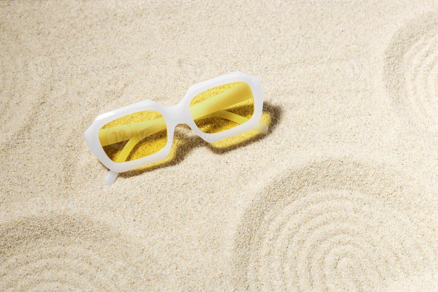 Modern White sunglasses on beach sand background at sunlight with shadow. Summer fashion eyeglasses with yellow glass. Summer vacation, summer rest concept. Minimal style trend flat lay photo