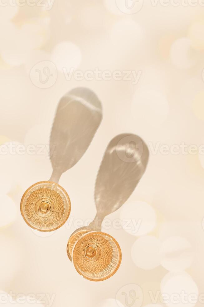 Wine glasses from color glass on beige flare bokeh background, shadow at sunlight. Summer alcohol drinks in trend wine glass goblets style, colored glassware. Top view aesthetic still life photo