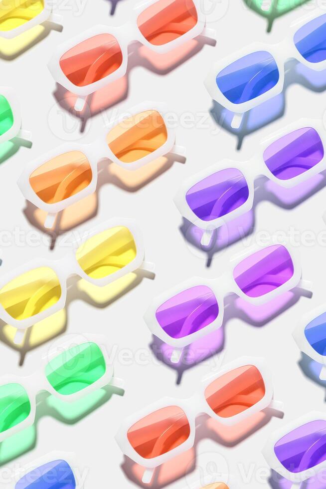 Minimal pattern from eyeglasses with rainbow colored glasses on white background, visual trends summer concept. Top view aesthetic photo, colored sunglasses as creative geometric pattern photo