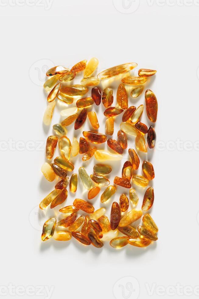 Natural gemstone amber stones with glare shadow, yellow orange colored on white background. Natural mineral Transparent amber gems, minimal flat lay pattern, creative top view, summer concept. photo