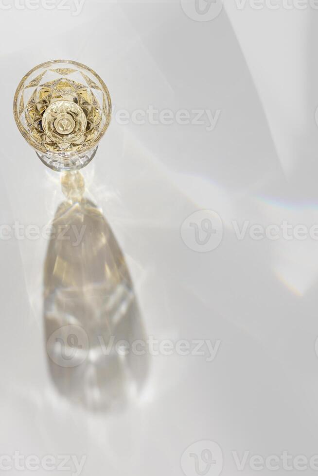 Top view of wineglass with white wine with beautiful shadows and reflections at sunlight, summer alcohol drink background, creative aesthetic flat lay, copy space, trendly still life for winery photo