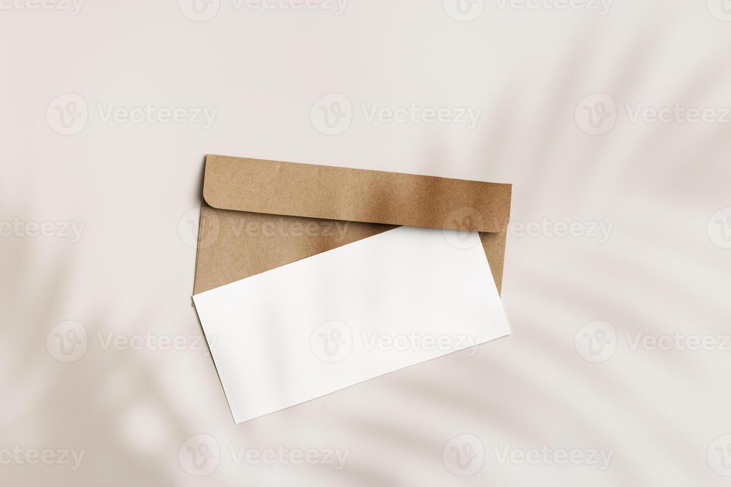 Blank paper card mock up and craft envelope on beige background and palm leaf shadow. White empty invitation on table. Minimal fashion lifestyle photo. Summer Flat lay, top view, copy space. photo