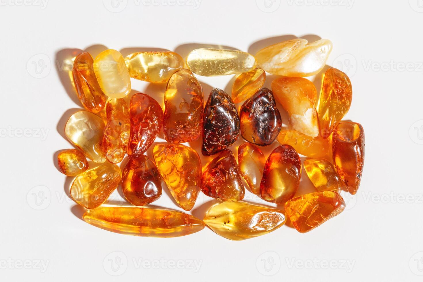 Natural gemstone amber stones at sunlight, yellow orange gradient color isolated white background. Natural mineral. Aesthetic lifestyle Amber gems, flatlay pattern, pieces ancient resin photo