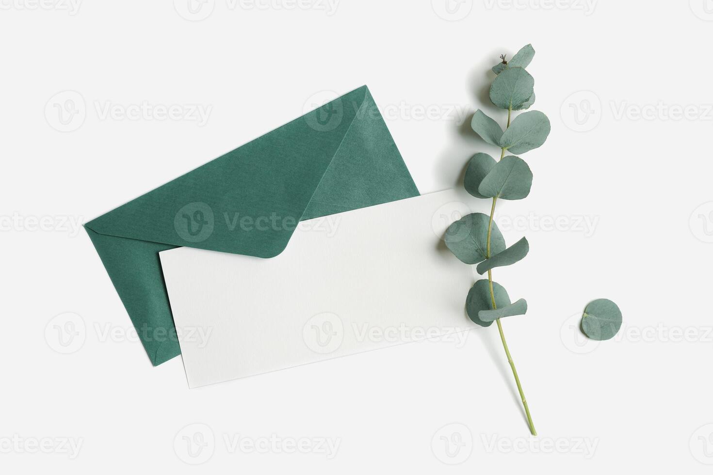 Teal envelope and empty paper card mock up with green plant leaves eucalyptus on white background. White blank letter on table. Minimal design stationery, flat lay template, top view, copy space. photo