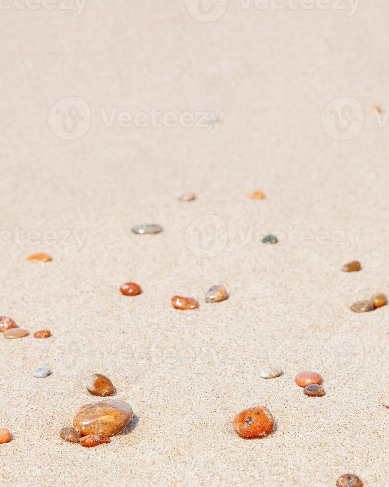 Natural stones amber yellow colored on beige sand. Aesthetic minimal nature scene with pebble stones on fine sandy background. Summer vacation or relaxation concept, selective focus. photo