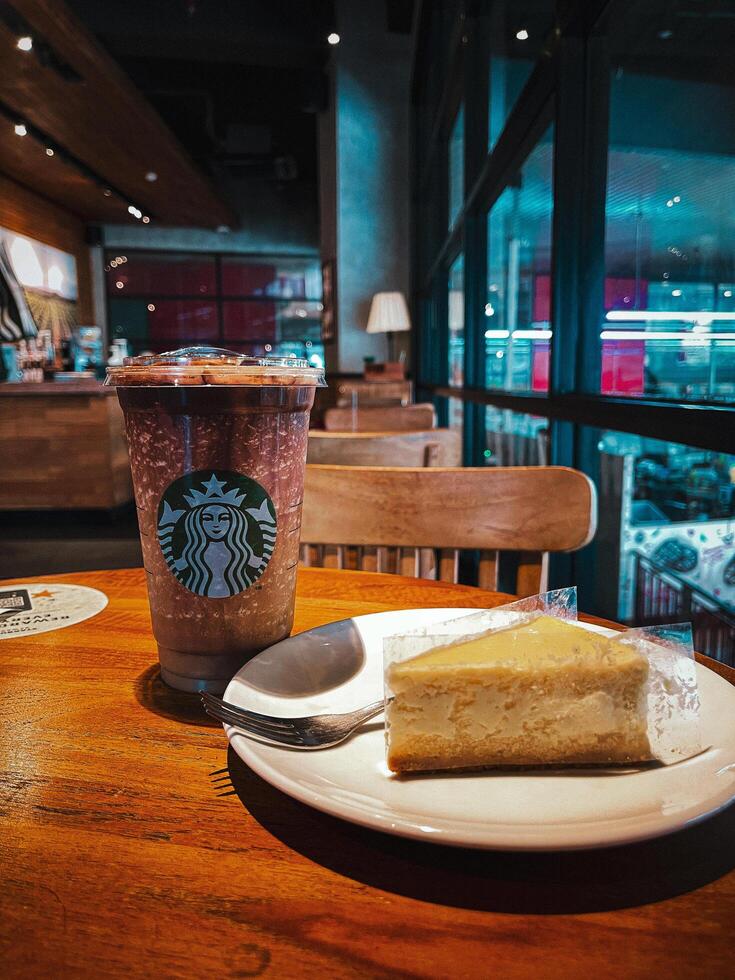 Starbucks Coffee Frappuccino with Cheesecake on a Wooden Table March 9, 2024 Bandung Indonesia photo