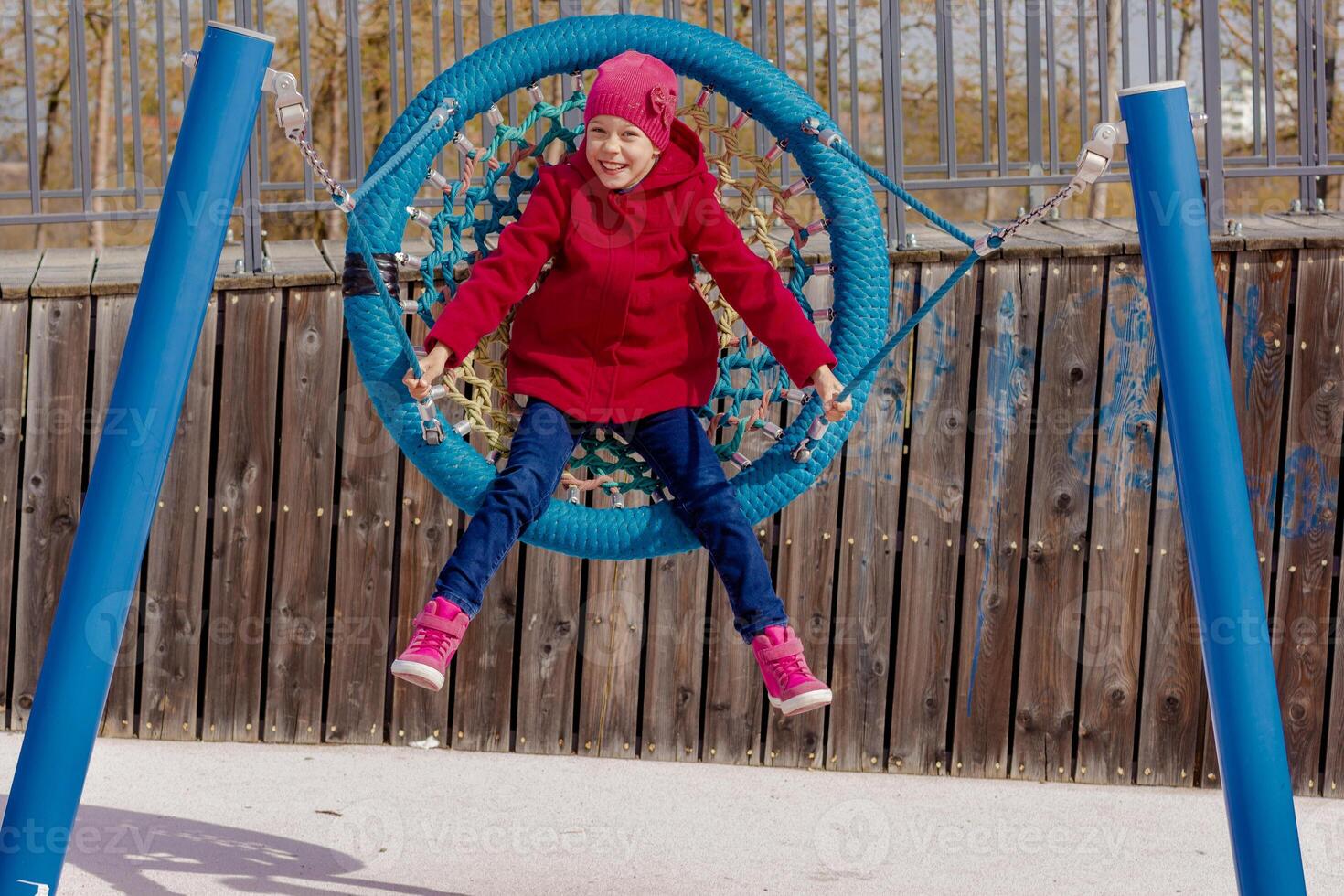 Caucasian smiling child of 8 9 years swinging on round seesaw looking at camera in motion photo