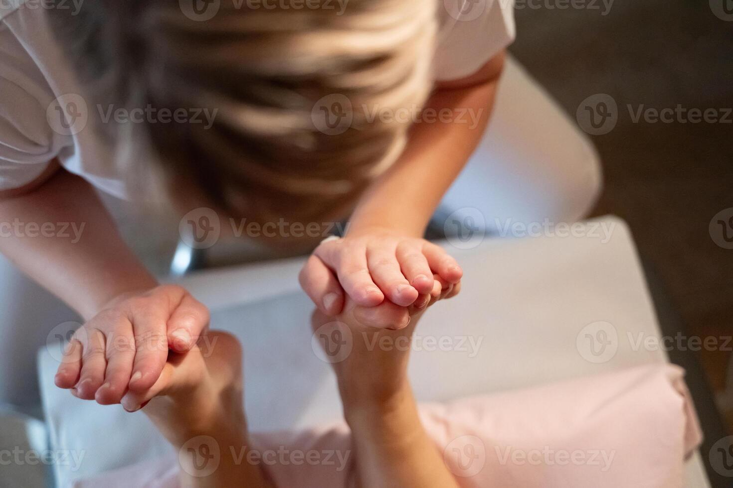 Foot Massage Therapy in a Relaxing Spa Setting. A professional massage therapist in a white uniform provides a soothing foot massage to a client in a calm and serene spa environment photo